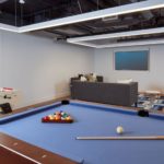 Club room with pool table, foosball, and seating around a TV