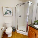 Bedroom with vanity and corner stand-up shower