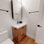 Bathroom with modern fixtures, walk-in shower, towel racks and hook, and sliding glass shower doors