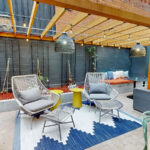 Allston Place courtyard chairs with foot stools and a pergola covering with hanging lights