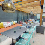 Allston Place courtyard lounge benches with tables and chairs covered by a wood pergola with hanging lights