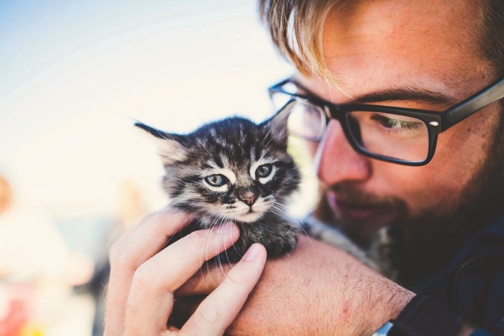 Man holding an adorable small kitten.