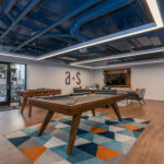 Clubroom with pool table, foosball, variety of seating and a wooden accent wall