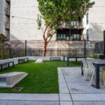 Courtyard with cornhole, grills, and table seating