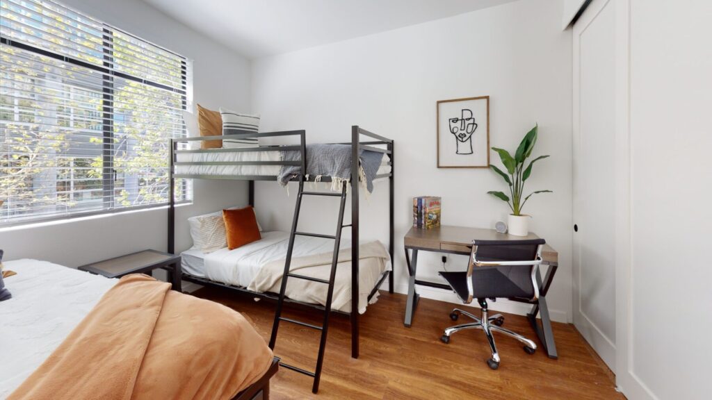 Bed, bunk beds, nightstands, desk, and rolling chair in
furnished Allston + Stadium bedroom.